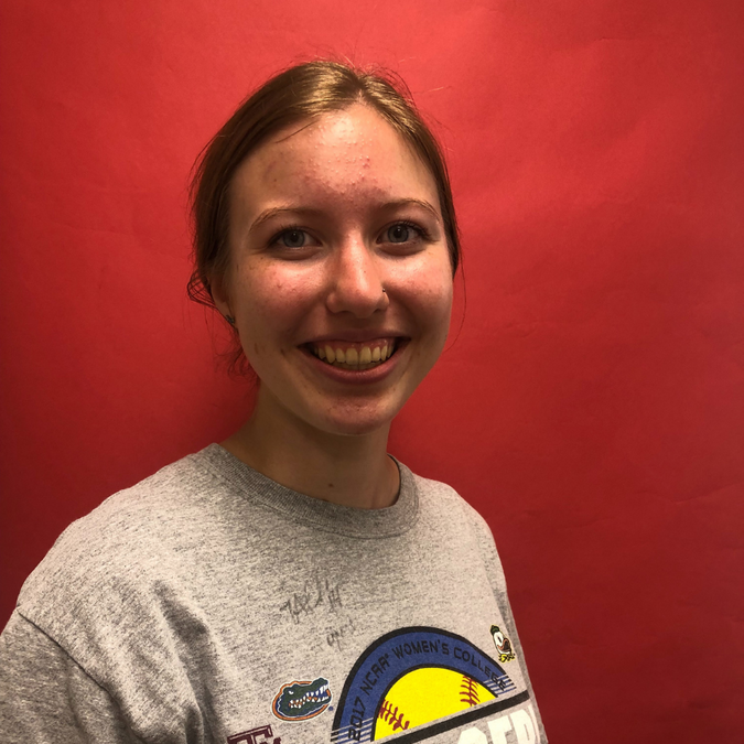 White presenting female, red background, grey shirt